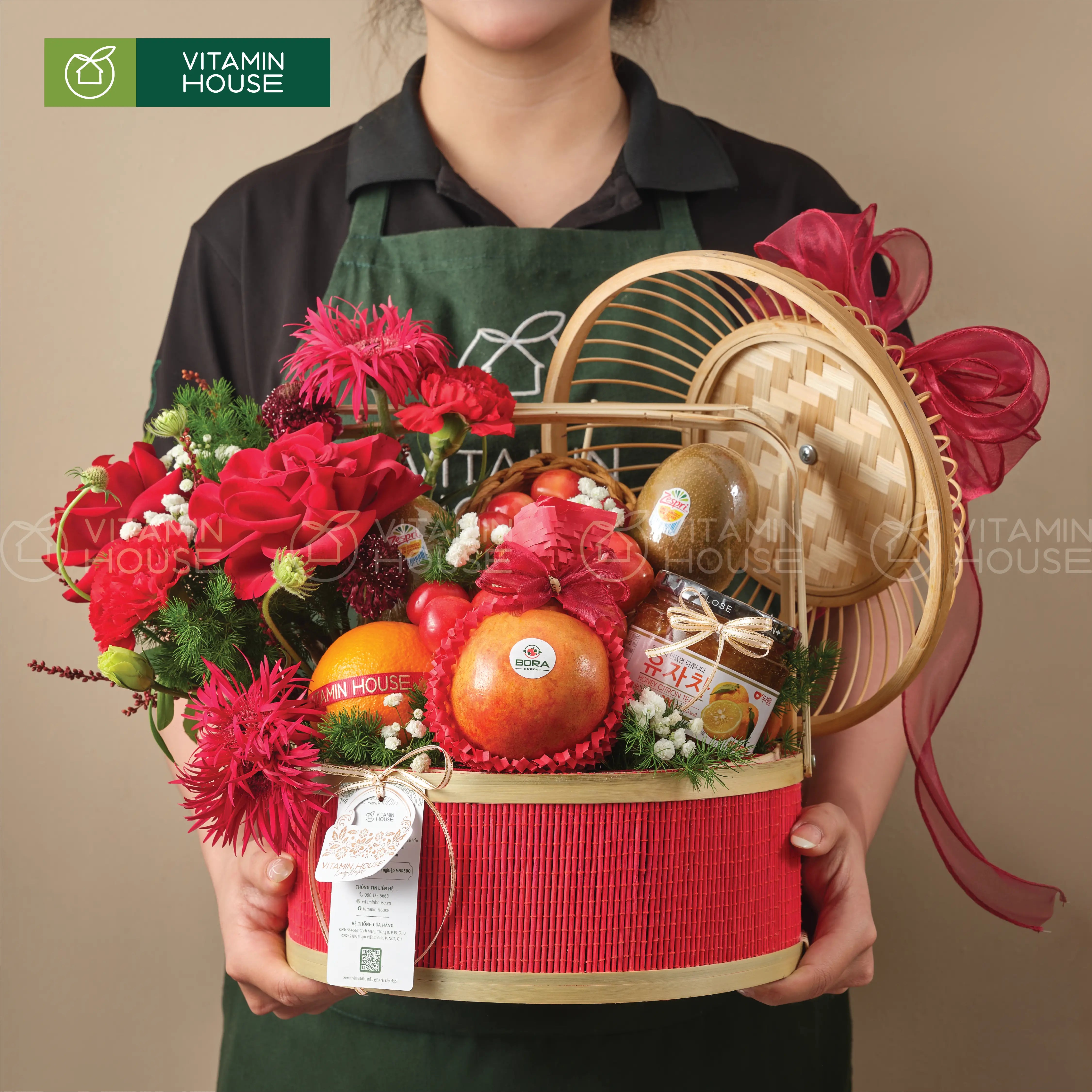 Hình ảnh giỏ quà cao cấp kết hợp hoa tươi, trái cây nhập khẩu trong làn tre đỏ trang nhã chụp hình cùng người